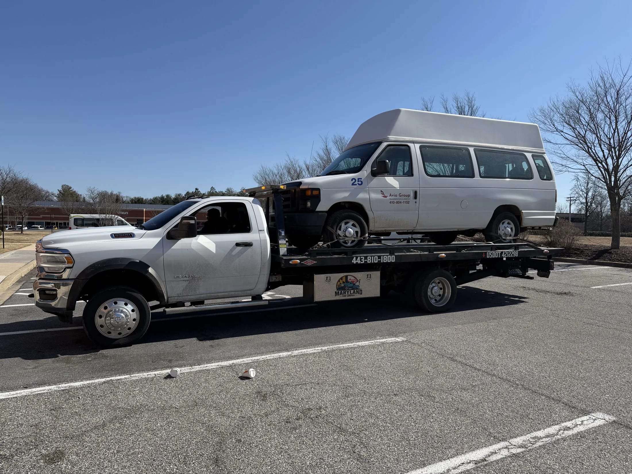 Maryland Tow Company flatbed truck transporting a passenger van